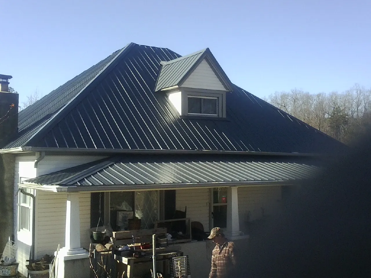 Dark blue standing seam metal roof with a dormer above a front porch in Kew Gardens