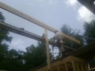 Carpenter setting a ridge beam over a new addition frame — Ice Dam Removal by Roofing Brothers in Kew Gardens