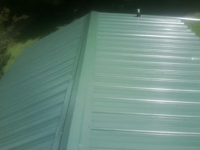 New green metal panels meeting at the ridge of a roof — Flat Roof Repair work by our crew in Kew Gardens