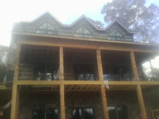 Dormers and porch framing on a large log home under construction — Roof Coating work by our crew in Kew Gardens