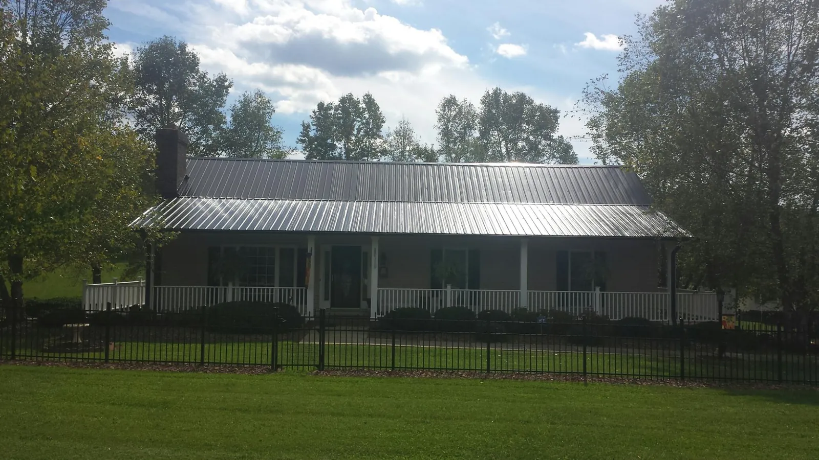 Gray metal roof on a brick ranch with a full width front porch — Gutter Guard Installation work by our crew in Kew Gardens