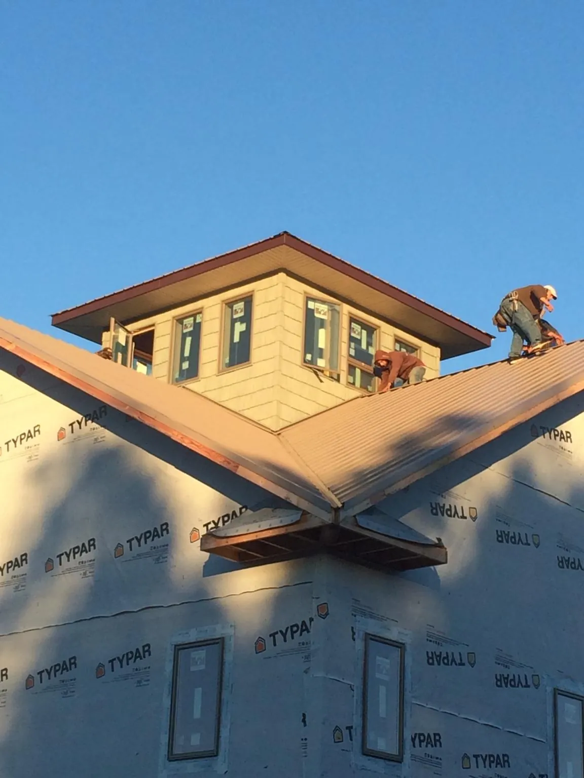 Roofers working around a rooftop cupola on a new metal roof at sunset — Roof Waterproofing in Kew Gardens by Roofing Brothers